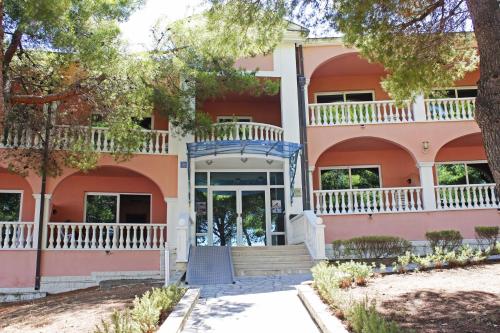 a pink building with a staircase in front at Marina Frapa Resort Rogoznica in Rogoznica