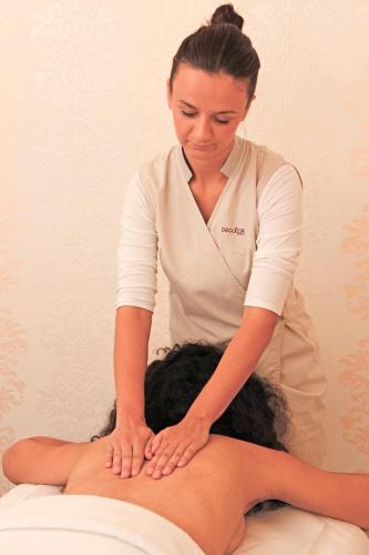 a woman sitting on the back of a persons back on a massage at Marina Frapa Resort Rogoznica in Rogoznica