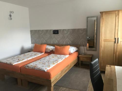 Hochfellner في سبيلبرغ: غرفة نوم مع سرير مع وسائد برتقالية ومرآة