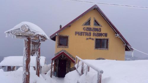 a building with a sign on it in the snow at Piatra Rancii in Ranca