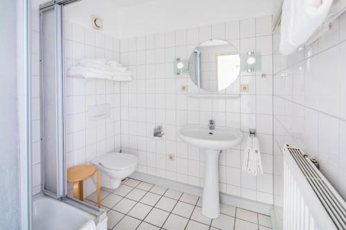 Baño blanco con lavabo y aseo en Birkenhof en Norderney