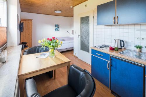 a kitchen with blue cabinets and a table with flowers at Birkenhof in Norderney