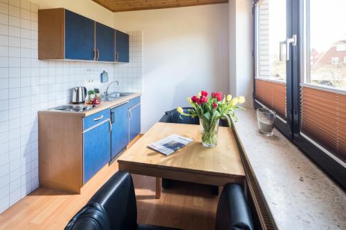 a kitchen with a table with a vase of flowers on it at Birkenhof in Norderney