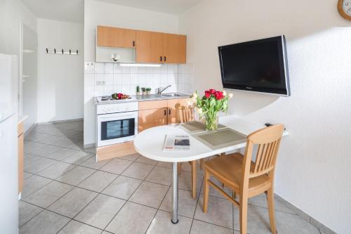 a kitchen with a white table and chairs and a tv at Birkenhof in Norderney