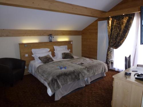 a hotel room with a large bed and a desk at Hôtel Restaurant "Les Sapins" Wellness & Gourmet in Manigod
