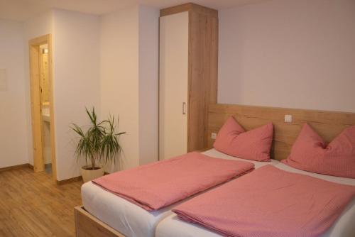 a bedroom with a large bed with pink pillows at Rauwieslhof in Walchsee