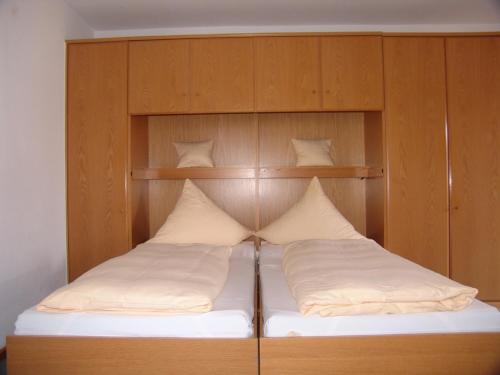 a bed with a wooden headboard with white pillows at Gästehaus Elisabeth in Bad Staffelstein