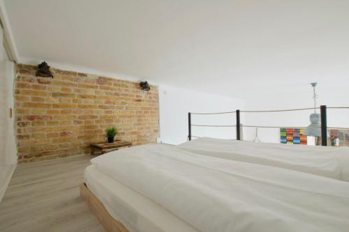 ブダペストにあるStandard Apartment by Hi5 - Wesselényi 8のレンガの壁の客室の白いベッド1台
