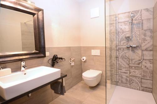 a bathroom with a sink and a toilet and a shower at Vinotel Dollt-Kern in Flemlingen