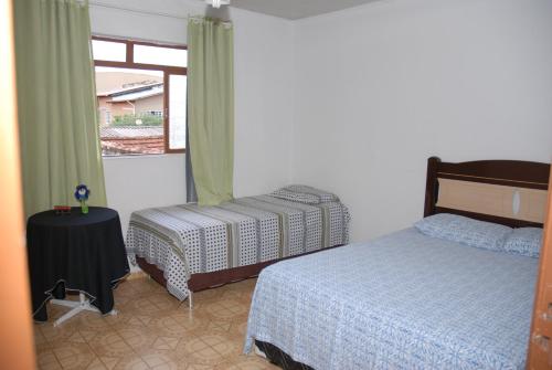 1 dormitorio con 2 camas y ventana en Pousada Ana Poipa en Goiânia