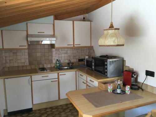 a kitchen with white cabinets and a table and a microwave at Haus Falger in Berwang