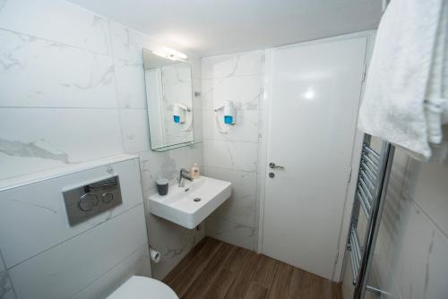 uma casa de banho branca com um lavatório e um WC em Artemis Luxury Apartment em Tessalônica