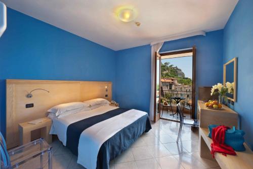 a blue bedroom with a bed and a balcony at Hotel Rivage in Sorrento