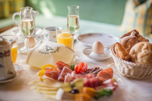 a table with a breakfast of bread and eggs and glasses of champagne at Kaisers Tanne - Premium Alles Inklusive Hotel in Breitnau