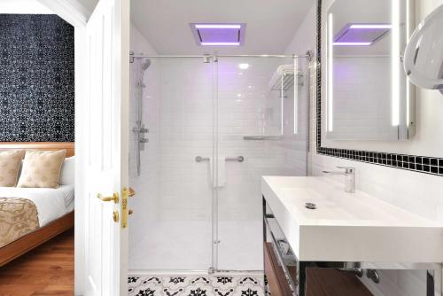 a white bathroom with a shower and a sink at Hotel Bonaparte in Montréal