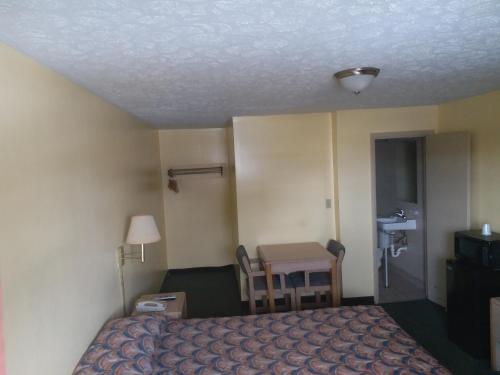 Habitación de hotel con cama, mesa y escritorio. en Westgate Motel, en Youngstown