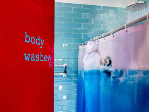 a bathroom with a shower with a sign that says baby washitzer at Hostel Tropico 20º in Cozumel