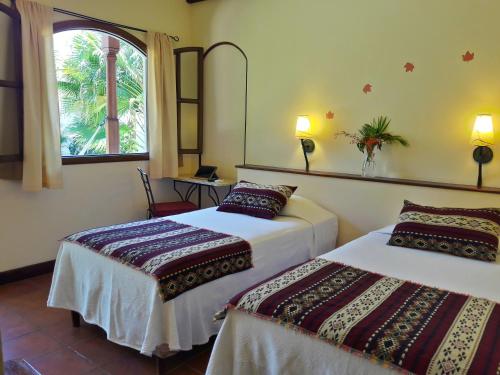 a hotel room with two beds and a window at Hotel Patio del Malinche in Granada