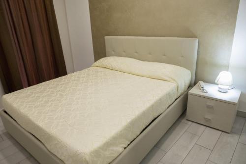 a bedroom with a white bed with a night stand at Barone Apartments in Sciacca