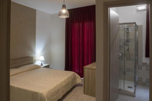 1 dormitorio con 1 cama y ducha con cortina roja en Barone Apartments, en Sciacca