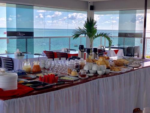 uma mesa com comida com o oceano ao fundo em Nord Easy Camboinha em Cabedelo