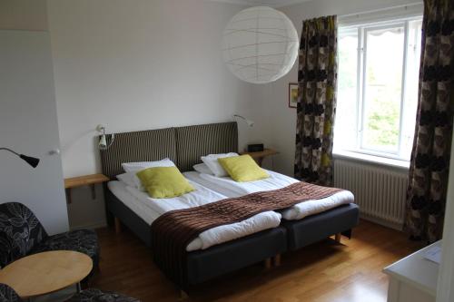 ein Schlafzimmer mit einem Bett mit gelben Kissen darauf in der Unterkunft Villa Ingrid in Borgholm