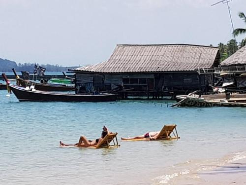 two people laying on beach chairs in the water at Mook Montra Resort Sea Front in Ko Mook