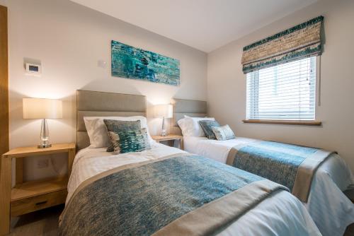 two beds in a bedroom with two lamps and a window at Dalriada Lodges Carlin in Stonehaven