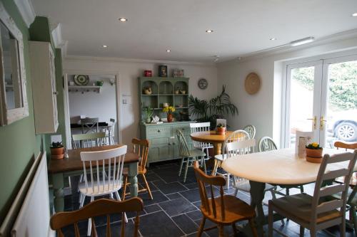 uma sala de jantar com mesas e cadeiras e uma cozinha em Olive Tree Guest House em Uttoxeter