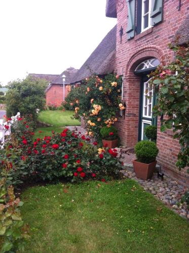 a brick house with flowers in a yard at Das Rosenhaus in Utersum