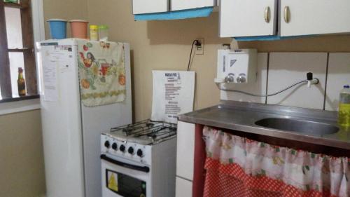 a kitchen with a stove and a sink and a refrigerator at Pousada Casa da Neuzita in Lençóis