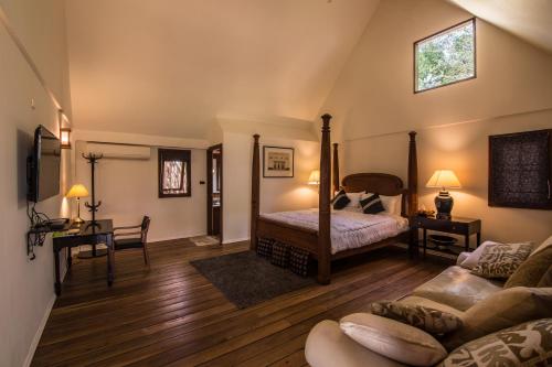 Teakwood villa في مدينة كانشانابوري: غرفة نوم مع سرير وغرفة معيشة