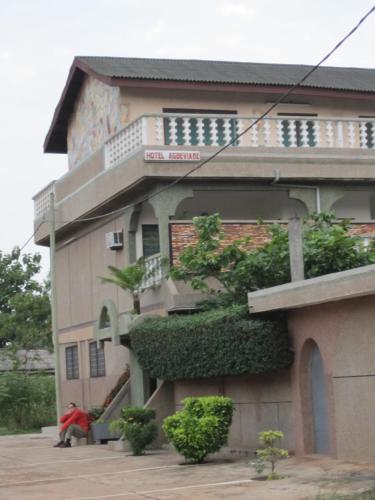 a building with a person sitting in front of it at Hotel Agbeviade in Palimé