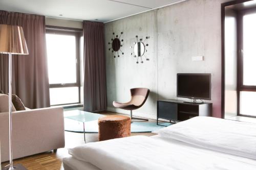 a bedroom with a bed and a chair and a television at Comfort Hotel Square in Stavanger