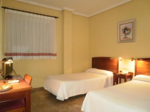 Pokój hotelowy z 2 łóżkami i biurkiem w obiekcie Hotel Isabel w mieście Almussafes