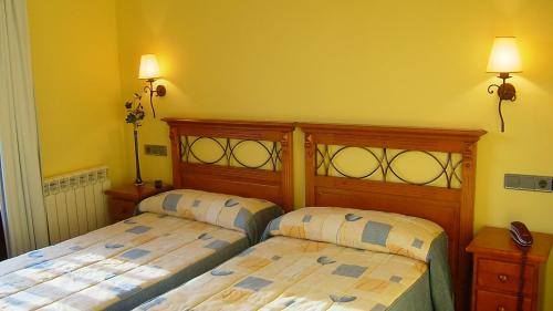 two beds in a bedroom with yellow walls at Hotel Virginia R.H. in Vinuesa
