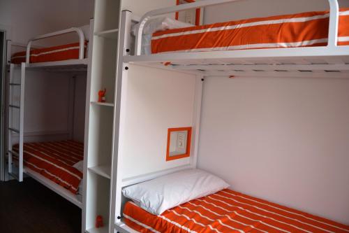 a bedroom with two bunk beds with orange sheets at Albergue Xabarín in Abadín