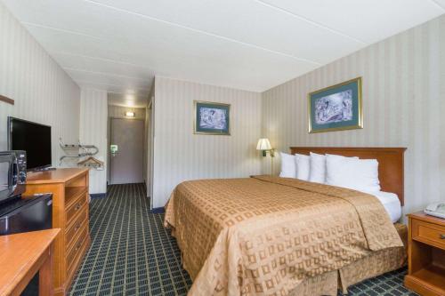 a hotel room with a bed and a television at Days Inn by Wyndham Columbus East Airport in Columbus