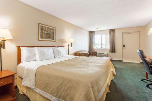 a hotel room with a large bed and a chair at Travel Inn - Mesa in Mesa