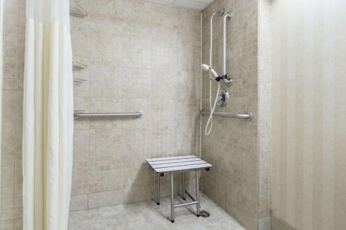 a shower with a stool in a bathroom at Days Inn by Wyndham Columbus East Airport in Columbus