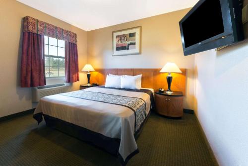 a hotel room with a bed and a flat screen tv at Days Inn by Wyndham Luray Shenandoah in Luray