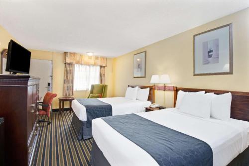 a hotel room with two beds and a flat screen tv at Days Inn by Wyndham Towson in Towson