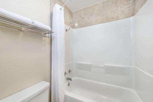 a white bathroom with a toilet and a sink at Days Inn by Wyndham Bryan College Station in College Station