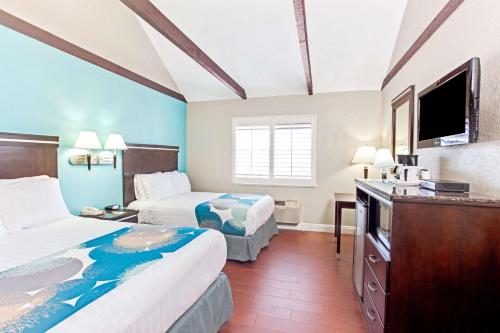 Habitación de hotel con 2 camas y TV de pantalla plana. en Cabana Inn & Suites, en Long Beach