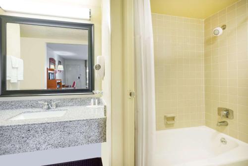 a bathroom with a sink and a tub and a mirror at Days Inn by Wyndham Paintsville in Paintsville