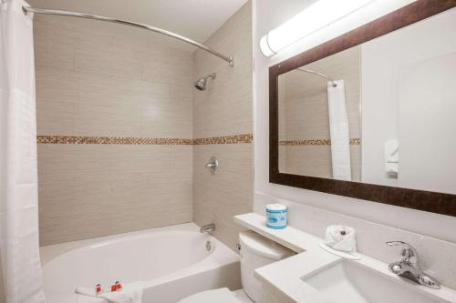 a bathroom with a tub and a sink and a toilet at Days Inn by Wyndham Orange Anaheim in Orange