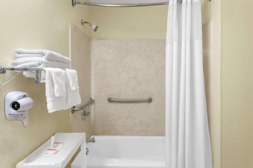 ein Badezimmer mit einer Dusche und einer weißen Badewanne in der Unterkunft Days Inn by Wyndham Columbia NE Fort Jackson in Columbia