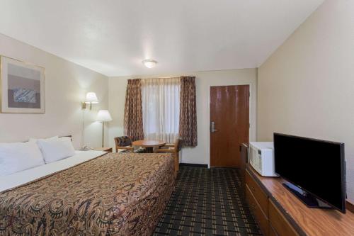 a hotel room with a bed and a flat screen tv at Days Inn by Wyndham Anaheim West in Anaheim