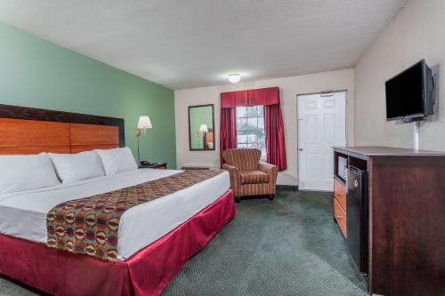 a hotel room with a bed and a television at Days Inn & Suites by Wyndham Lexington in Lexington
