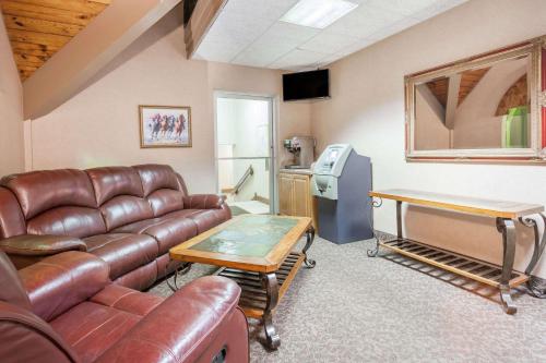 a living room with a leather couch and a table at Days Inn & Suites by Wyndham Lexington in Lexington